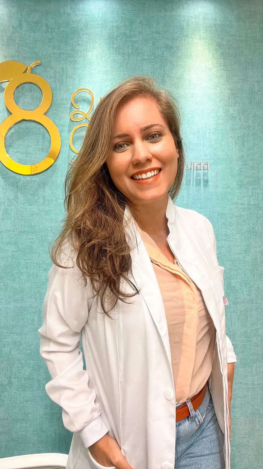 Dra. Giselle Pereira sorrindo em frente ao logotipo da clínica